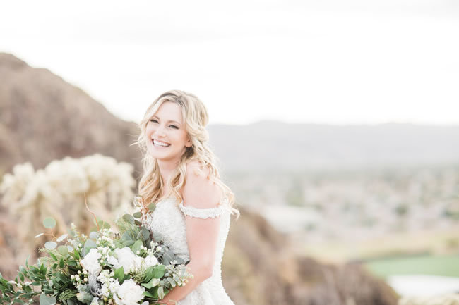 Bride smiling outdoors with big green and white bridal bouquet