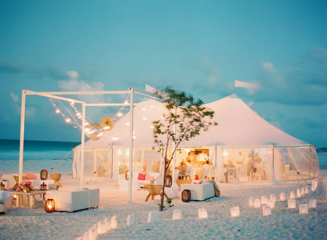 A tented beach wedding reception on the sand