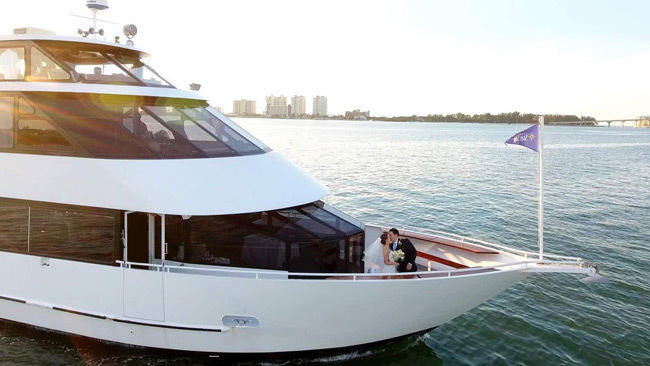 Tips for Planning a Wedding on a Boat | Newlyweds kiss on the bow of a yacht