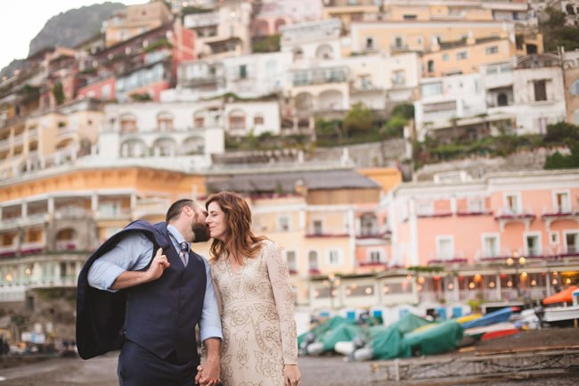 Newlyweds kiss in front of colorful homes in Positano, Italy