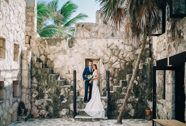 A beautiful couple poses in front of ruins in Tulum, Mexico