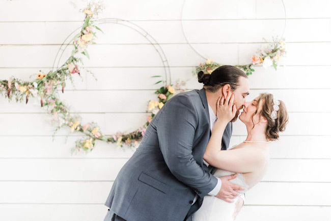 Newlyweds share a kiss in front of floral hoops | Elopement Checklist