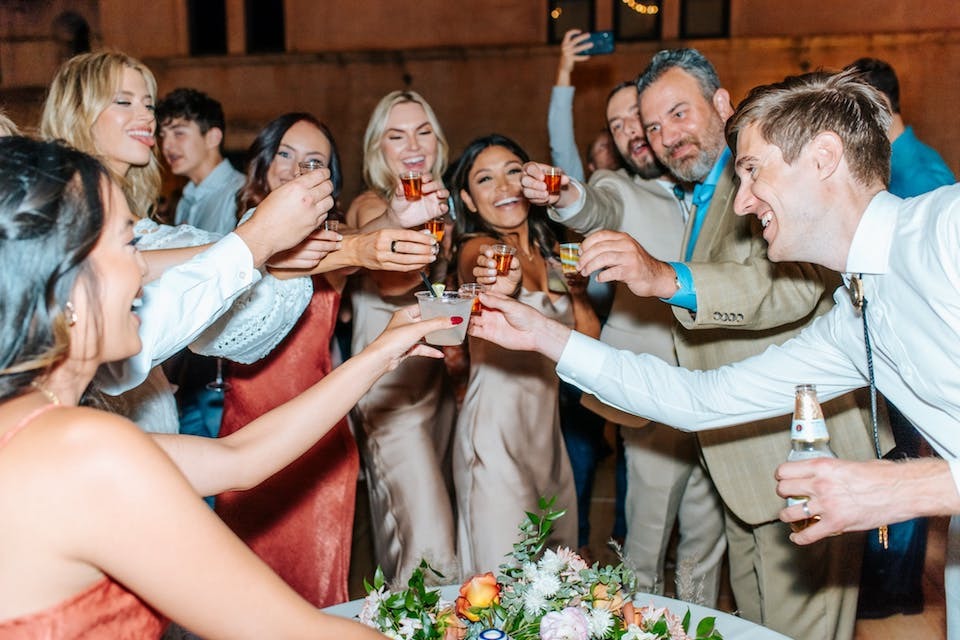 A happy wedding party cheers-ing with shots at Tlaquepaque Arts and Shopping Village