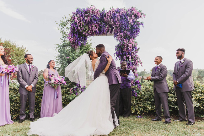 Newlyweds kiss under floral ceremony arch | What To Look For in a Wedding Photographer