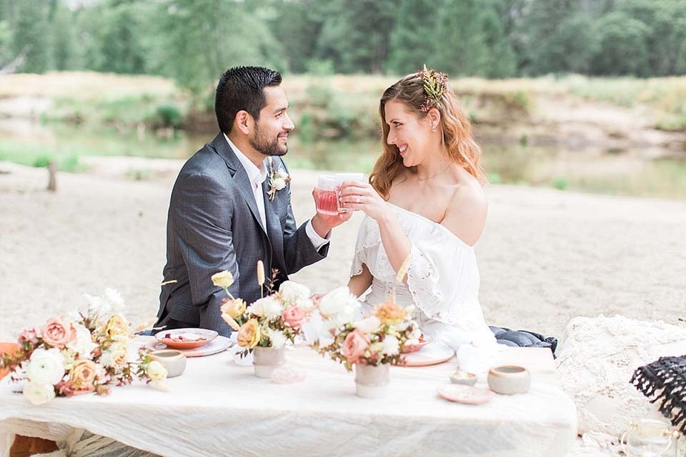 Wedding Hidden Fees | A newlywed couple cheers during their outdoor elopement picnic reception