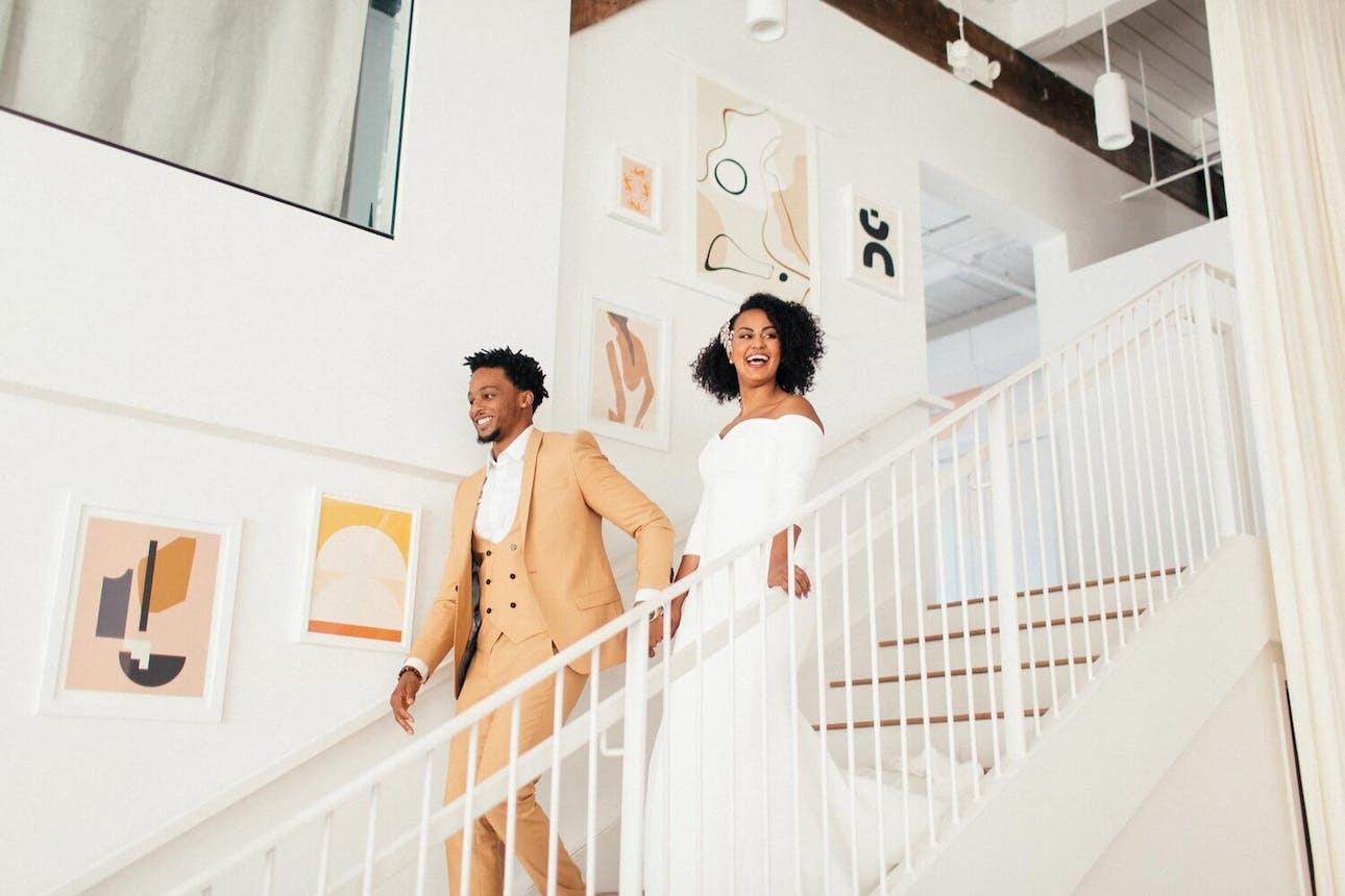 Bride and groom walking down the stairs of their art gallery wedding | Wedding Budget Tips