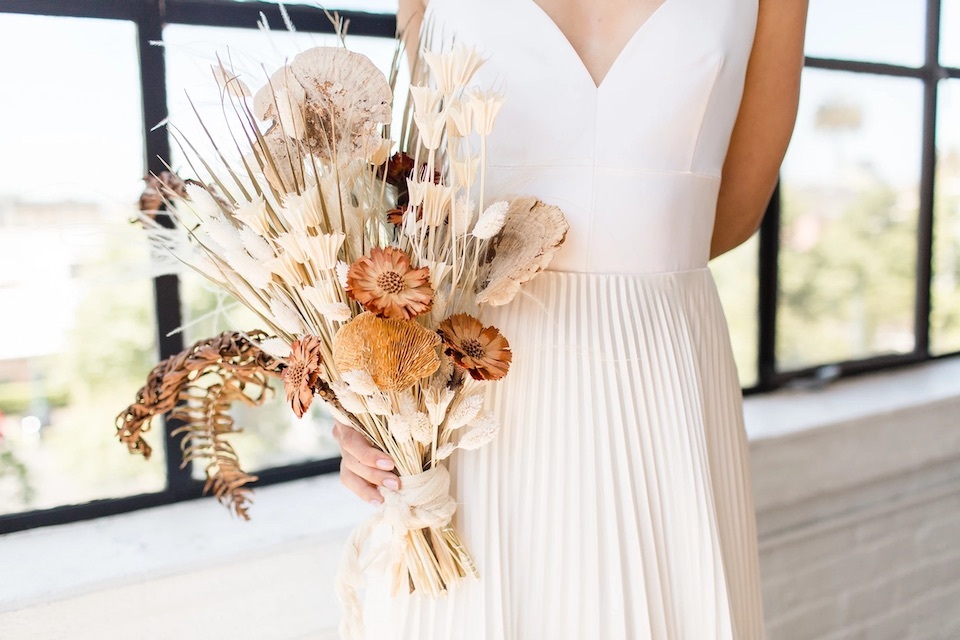 A bride holds a dried flower wedding bouquet | Cheap Wedding Ideas