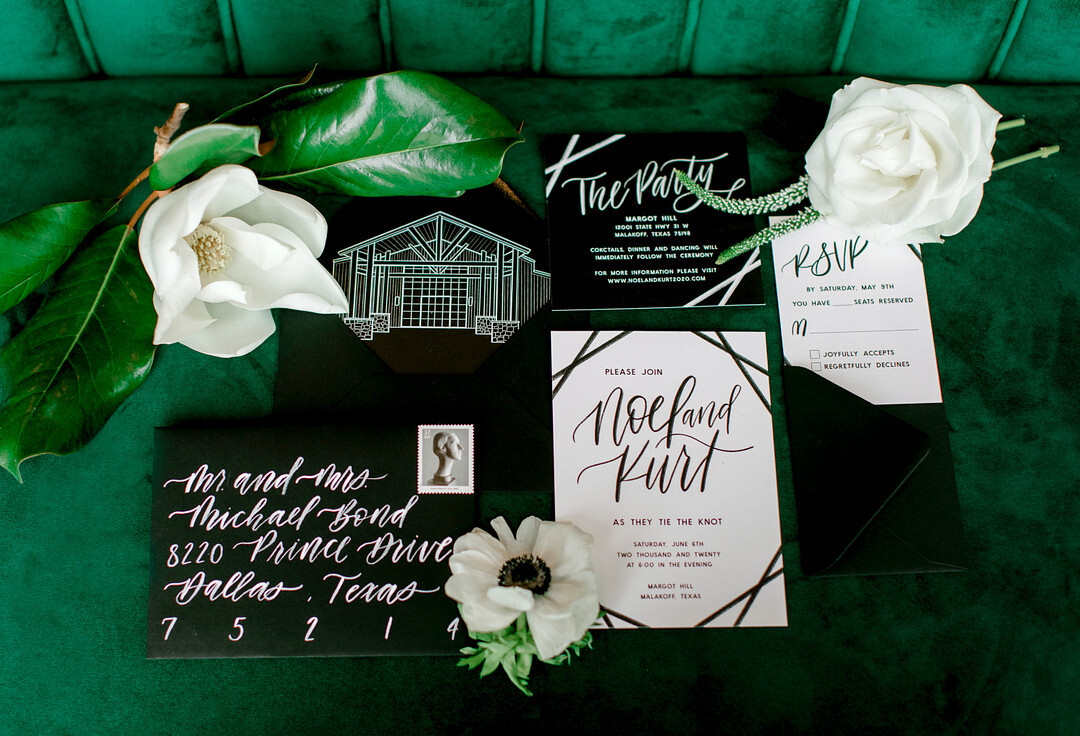 Black and white modern wedding stationery suite on a green velvet couch